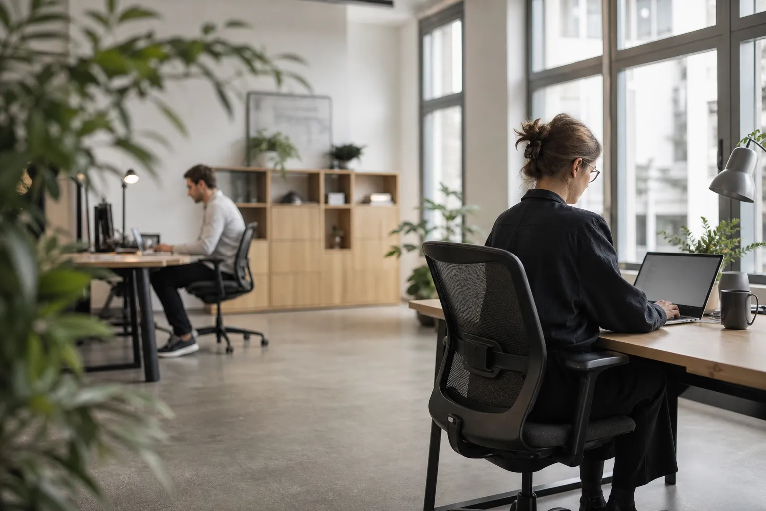 Vue large d'un espace de travail commercial ouvert, deux personnes au travail.