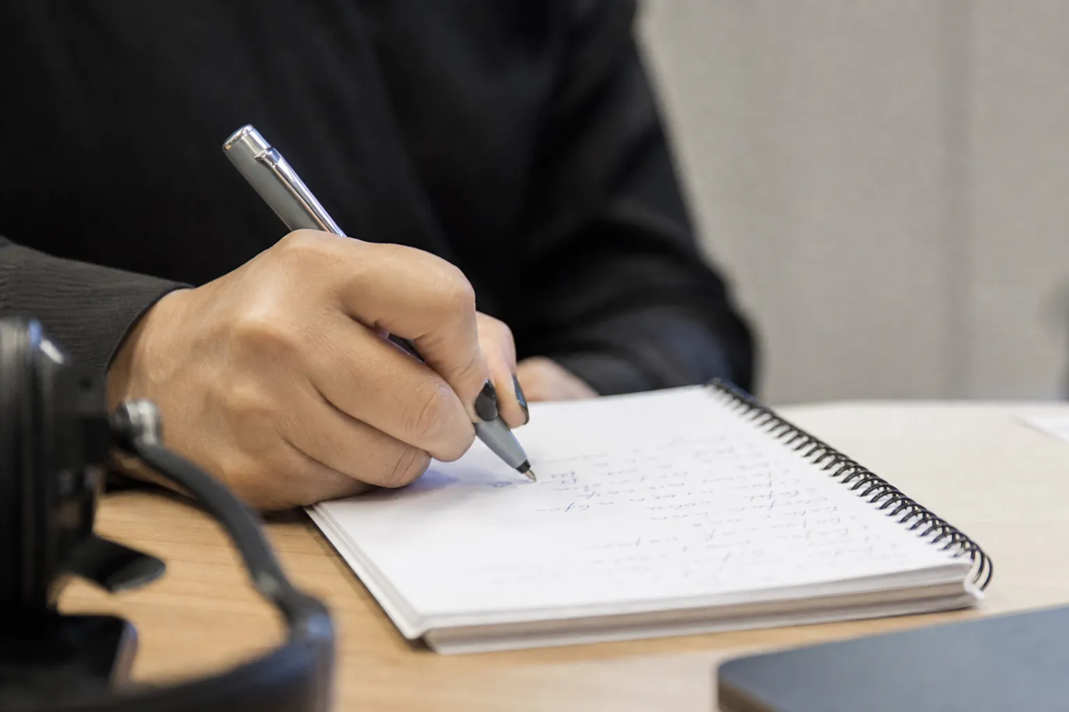 Une main note rapidement quelques mots sur un carnet pendant un appel.